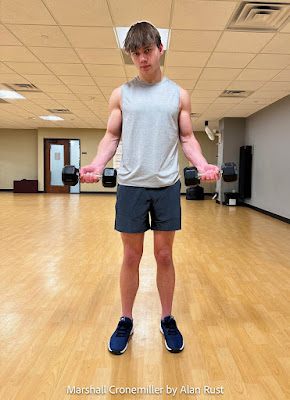 Marshall standing in the gym holding dumbbells