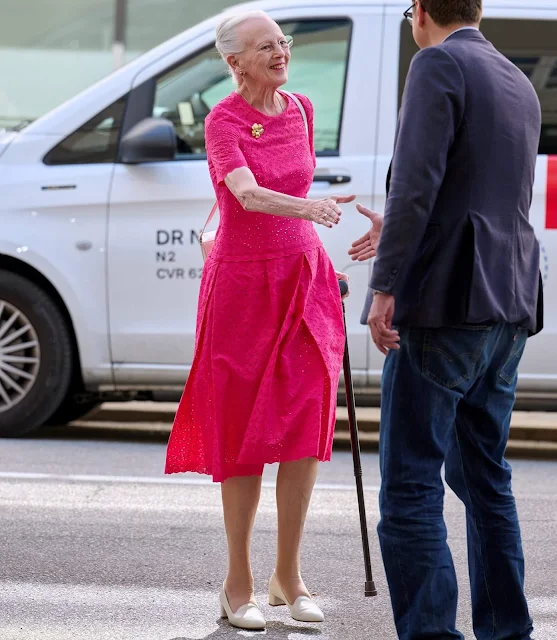 Queen Margrethe wore a fuchisia pink lace midi dress. Golad flower brooch. Gold earrings. Danish poet Caspar Eric