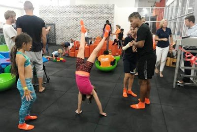 Girl doimg hand stands while trainer is looking on 