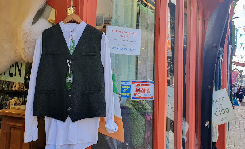 Dark-green woollen waistcoeat modelled over an oversize white shirt in a Galway city wool-clothing store - beside a staff-wanted advertisement