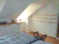 Schlafzimmer unter der Dachschräge mit Holzbalken