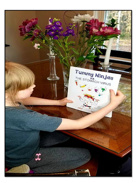 Daughter Ava reading the cover of Tummy Ninjas vs the Stomach Virus