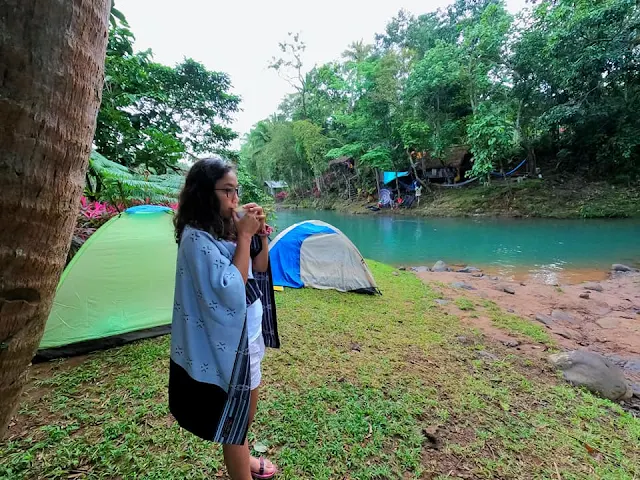 girl camper having coffee beside the river tent camping