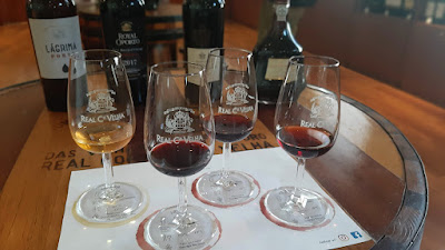 Quato copos com vinho junto à quatro garrafas de vinho do Porto da Real Companhia Velha