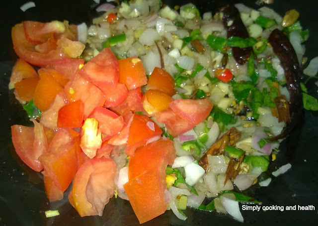 Adding curry leaves, green chili and red chili, tomatoes .