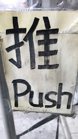 A storefront door has a sign affixed to it in Mandarin Chinese and in English for "Push" 