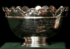 A silver bowl with scalloped edges and extensive text engraved on its side.