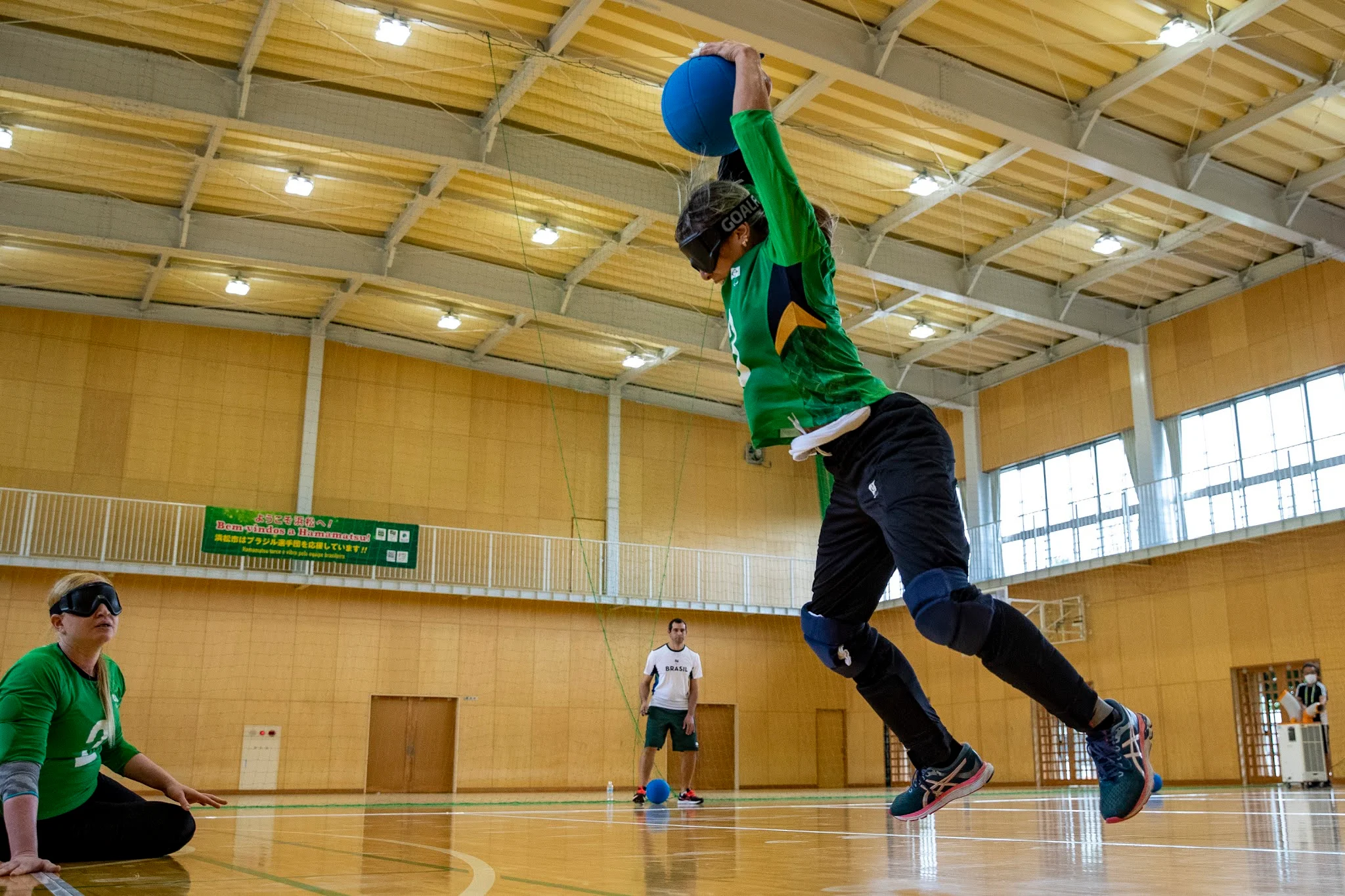 Jogadora brasileira com a bola acima da cabeça se preparando para um arremesso durante treinamento