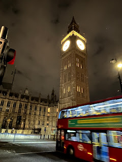 Elizabeth Tower (Big Ben) bij nacht met verlichte klok, dubbeldekkerbus rijdt langs