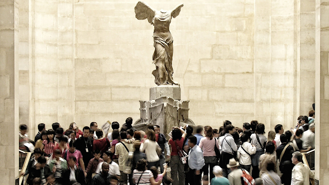 Nike de Samotracia admirada por los visitantes del Louvre
