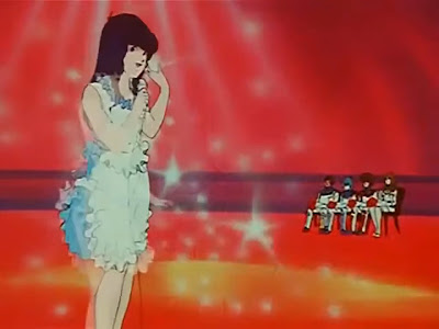 Minmay performs for the newly anointed heroes. Character art is noticeably less detailed than in previous episodes.