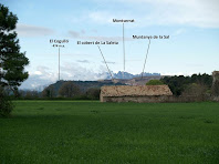 Imatge d'un cobert de La saleta amb la Muntanya de la Sal i Montserrat al seu darrere, des del Pla de Serra-sanç