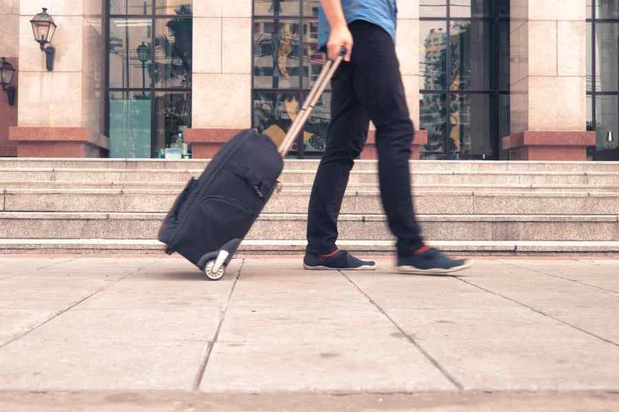 A man pulling a suitcase on wheels along a street