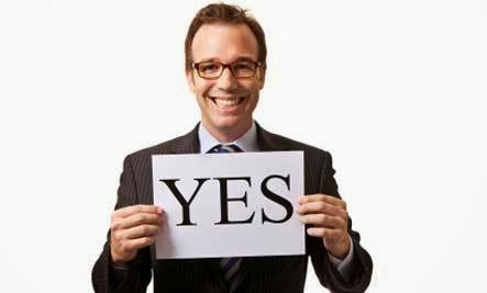 Guy smiling holding a piece of paper that says yes