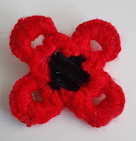 Red poppy with a black center made from pop tabs, yarn, and a black pipe cleaner.
