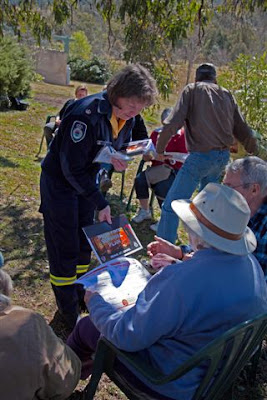 Jayne talks to seated community members while handing out a Bush Fire Survival Plan.