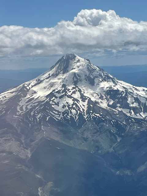 A view from the plane of Mount Hood. The mountain is snow covered at its peak.