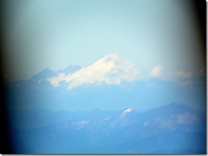 From the air and approaching Seattle, Mount Ranier above the clouds and through the airplane window.