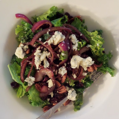 Warm Kale Salad:  A salad made of red onions sauteed in oil and balsamic vinegar mixed with kale and topped with blue cheese, toasted pecans, and dried cranberries.