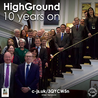 A group of smartly dressed people standing on stairs all looking and smiling at the camera. Text reads: HighGround 10 years on