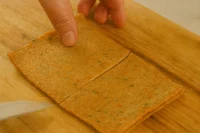 Fish cake being sliced on a wooden cutting board