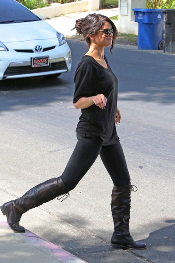 Woman wearing a black t-shirt, black leggings and black long combat boots