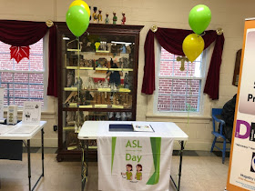 Table with banner "ASL day" and papers showing basic ASL