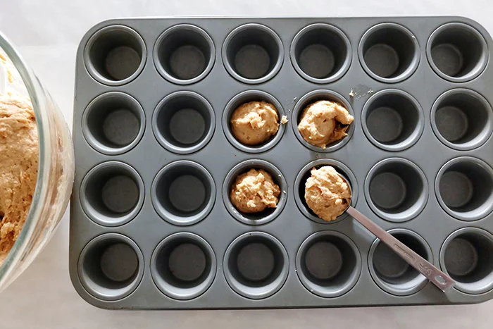 portioning out peanut butter bacon pupcake batter in mini muffin tin