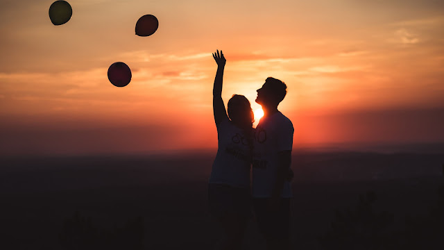 Couple happy together with baloons at sunset