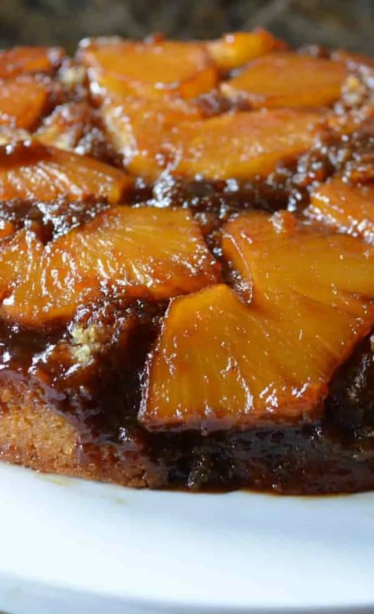 A side semi over head photo of a baked Fresh Pineapple Upside Down Cake on a white cake stand.