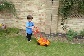 Child cutting the grass with pretend lawnmower