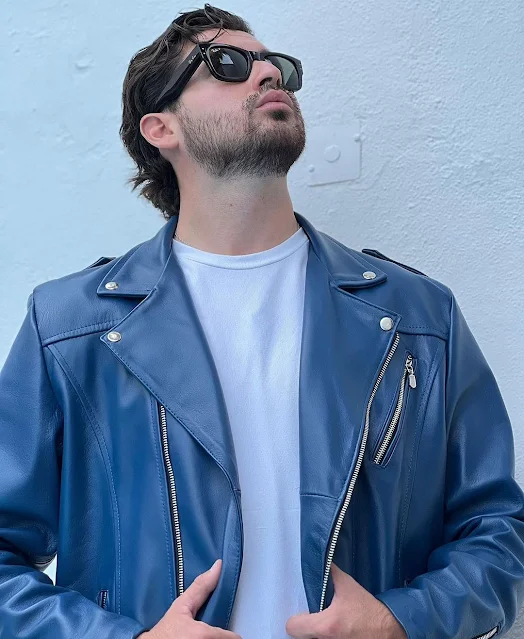 A sky blue leather biker jacket worn by some hot dude whose head is wearing sunglasses and staring up at the Sun dirty blonde medium length hair Superior view from below