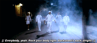 A group of guys dressed in white walking towards the camera with the text Backstreet's Back underneath