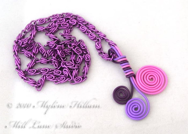 Pink and purple spiral wire pendant on a purple aluminium chain.