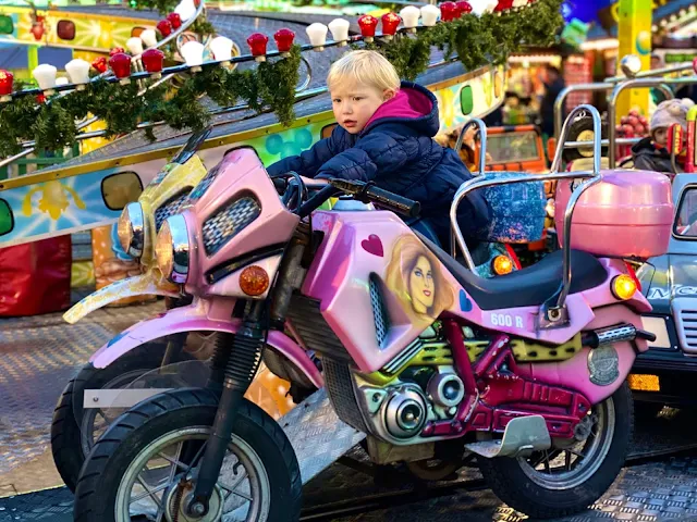 A 3 year old child on a bike on a ride while visiting winter wonderland