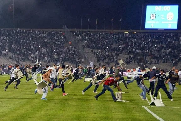 Beşiktaş fans throw chairs and run onto the pitch during a match against Galatasaray