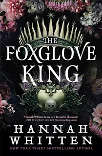 Book "The Foxglove King". A dark and intricate cover. Above the title, a metal circlet with star - tipped spikes that look like daggers. Below the title, a silver bust or monument with a skull motif. Across the top of the cover, delicate flowers in pinks, greys and white.