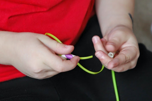 stringing paper straws to make necklaces