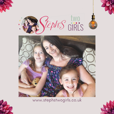 brown haired white mum cuddling two young girls, all smiling broadly at the camera