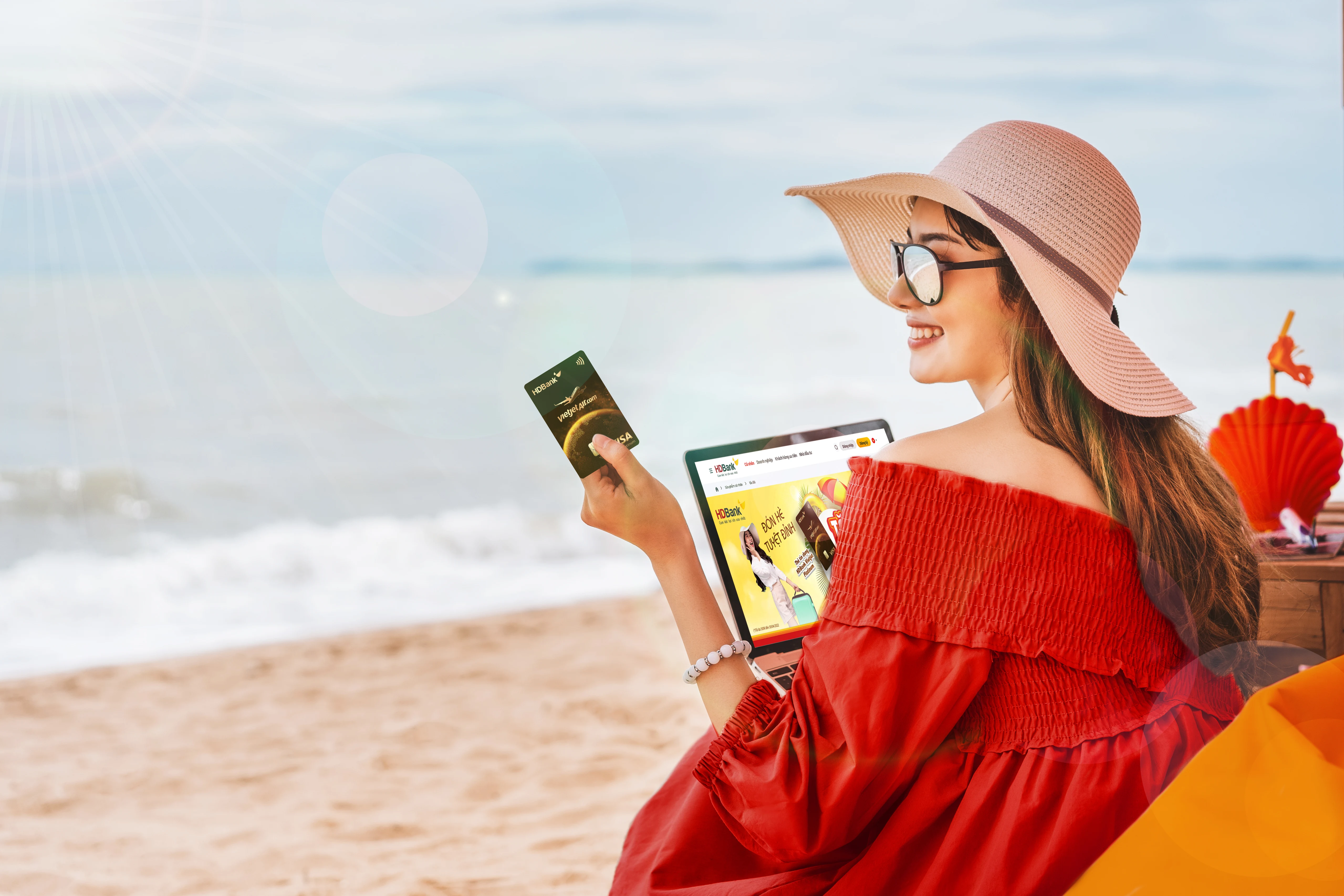 tourist woman in red and hat sitting in a beach holding a card and computer tablet