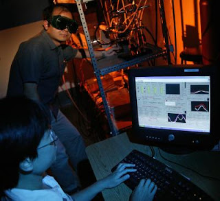 Caption: Graduate students Ganhua Lu (in back) and Ming Liu operate the equipment called a mini-arc plasma reactor