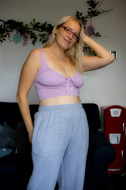 A female wearing a lilac crop top and grey over sized jogger bottoms