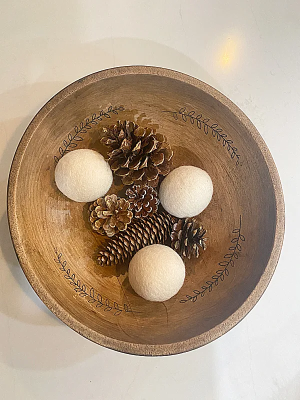 wooden bowl with dryer balls and pinecones