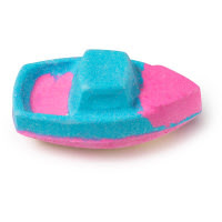 A bright pink boat shaped bath bomb with a bright blue outline on the edges of the bath bomb on a white background. 