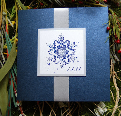 The folded card is in a dark metallic navy with a satin silver ribbon accent