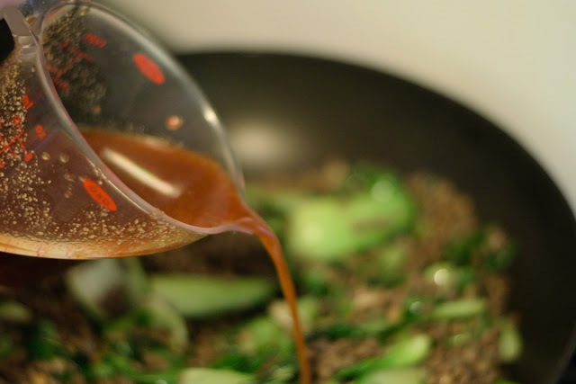 The stir fry sauce being added to the frying pan.