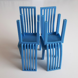 Four one-twelfth scale modern miniature plastic dining chairs with high backs.