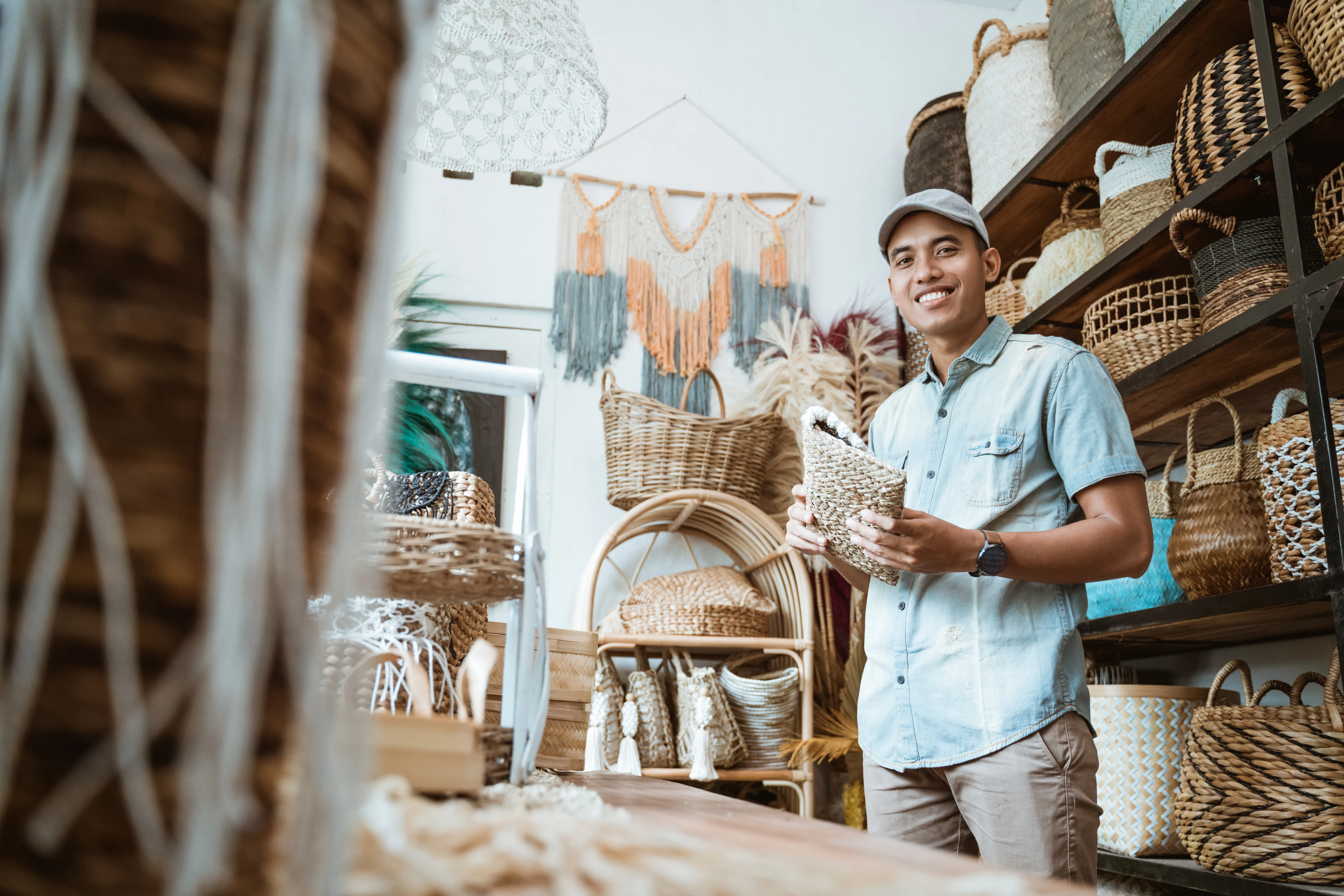 jovem empreendedor sorri enquanto segura uma carteira de vime em uma loja de artesanato