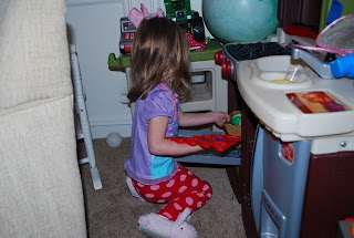 Preschooler putting cookies in the oven for her little dolls