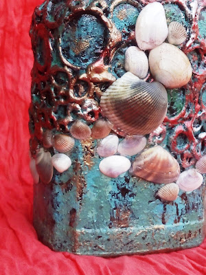 A hint of copper and bronze highlights the textures created by glue gun on this recycled bottle